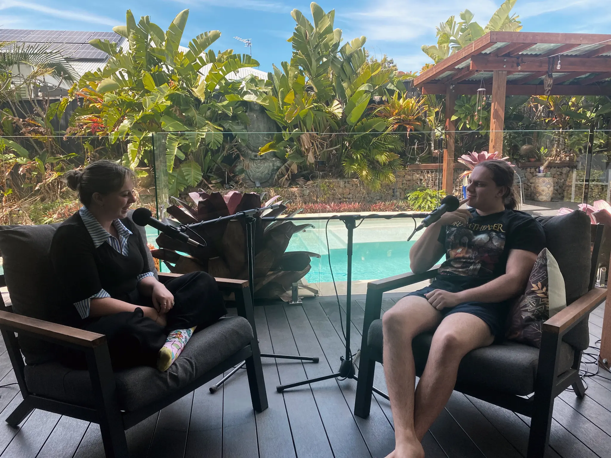 Two people recording a conversation with microphones in an outdoor setting